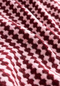 Tissu tricoté en motif pied-de-poule bordeaux et rose, présentant une surface douce et texturée avec des fibres visibles et une apparence drapée.
