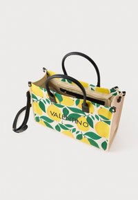 Καμβατζής τσάντα με σχέδιο λεμονιού και φύλλων σε κίτρινο και πράσινο χρώμα. Μαύροι χειρολαβές και χρυσά υλικά τονίζουν το σχέδιο.