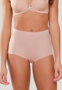 Ropa interior de tiro alto y sin costuras en tela beige claro con textura suave y cintura elástica. Sin patrones visibles ni accesorios.