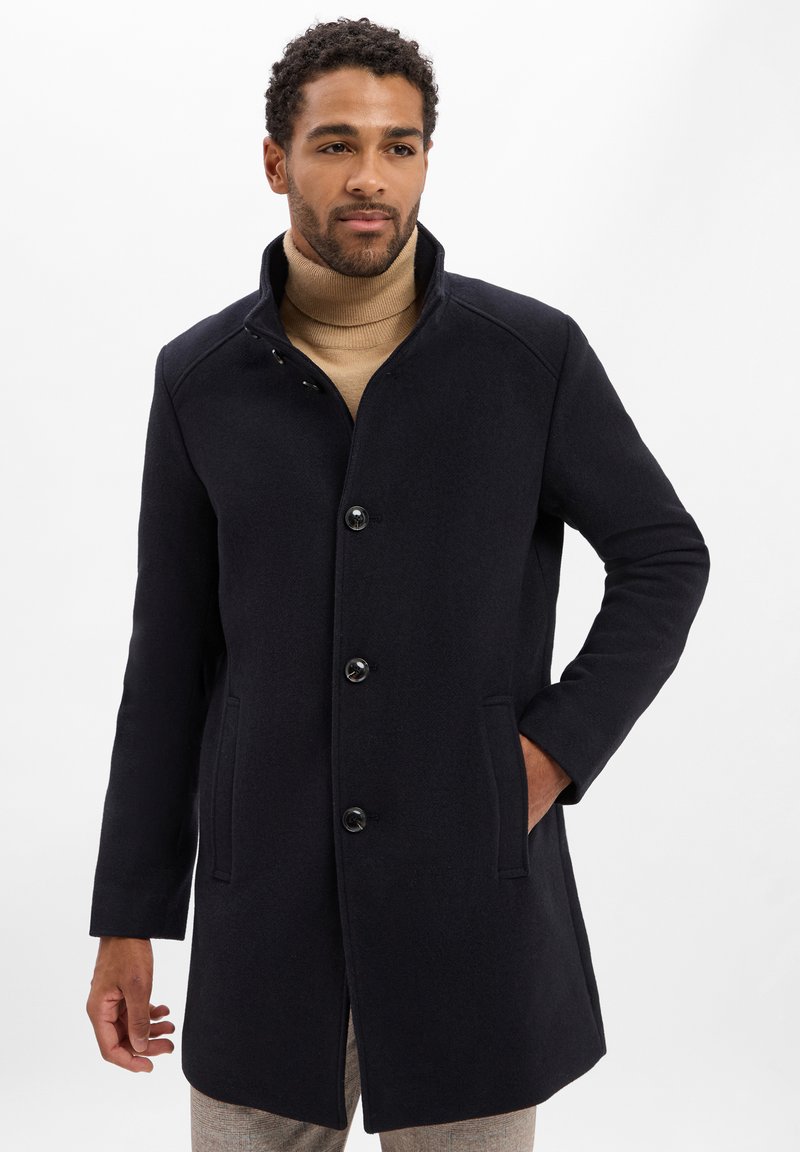 Marineblauer Wollmantel mit hohem Kragen, vorderem Knopfverschluss und Seitentaschen. Bietet eine taillierte Passform und strukturierten Stoff.