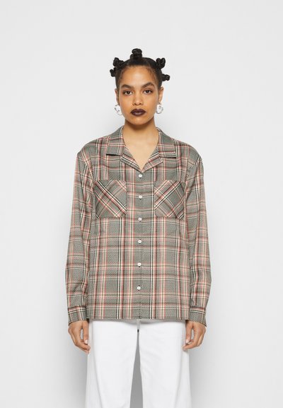 Camisa de botão xadrez em cinza, vermelho e verde; apresenta dois bolsos no peito, mangas longas e colarinho; o tecido tem um acabamento texturizado.