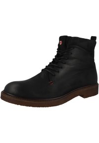Botas de cuero negro para el tobillo con punta redonda, diseño con cordones, costuras de acento rojas y suela de goma marrón. Presenta una tira para facilitar el calzado en la parte posterior.