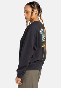 Black crewneck sweatshirt with a relaxed fit, featuring a colorful wave and flower graphic on the back. Ribbed cuffs and hem.