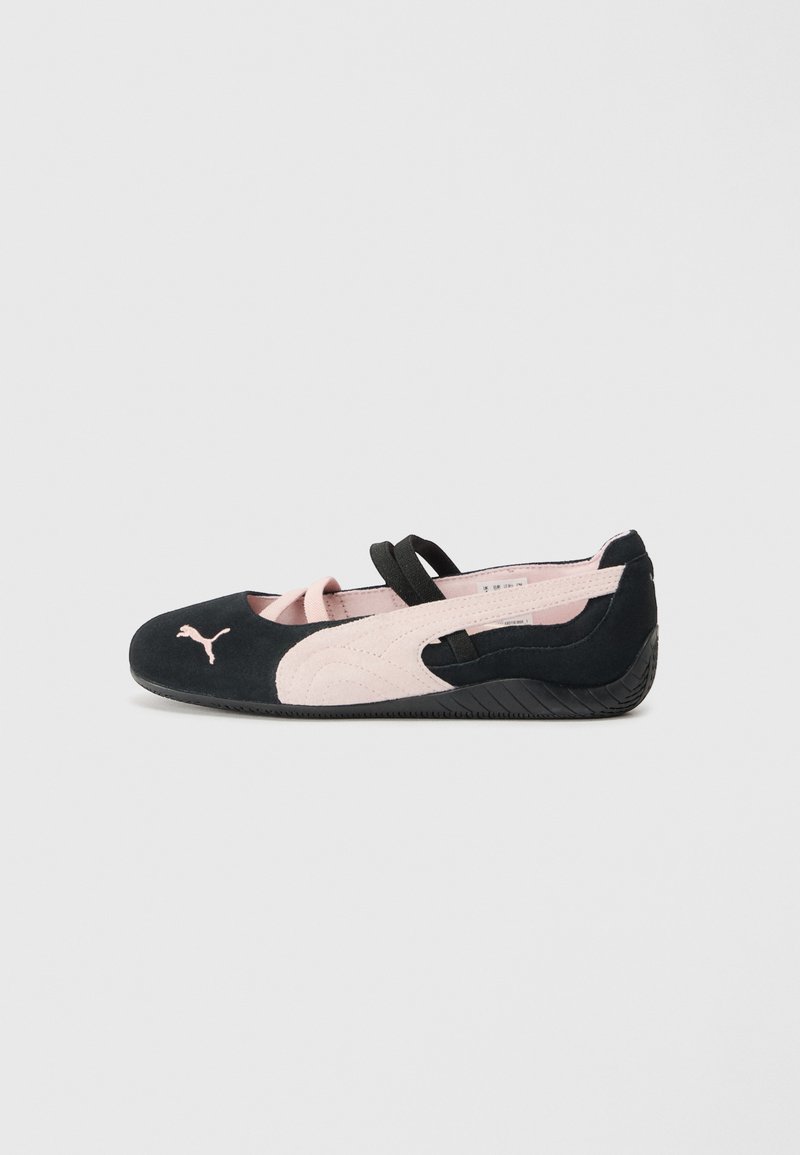 Black and light pink suede flat shoes with elastic straps, rounded toe, and textured rubber sole, featuring a small logo on the front.