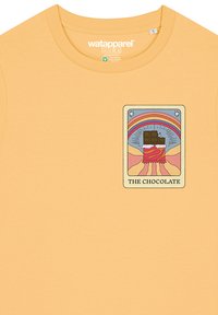 Geel katoenen T-shirt met een kleurrijk grafisch label met chocolade- en regenboogontwerp. Ronde hals, korte mouwen, zachte textuur.