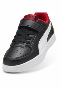 Juodas odinis sportbačių modelis su raudonomis detalėmis, baltu baltu ir perforuota pirštine. Yra kilpos ir kilpos diržas bei tekstūruoti juodi raišteliai.