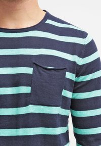 Pitkähihainen raitapaita, jossa on tummansinisiä ja mintunvihreitä vaakaraitoja, pyöreä pääntie ja hieman tekstuuria oleva rintatasku.