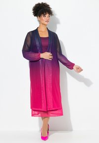 Genomskinlig lång jacka i övergångsfärger från mörklila till klarrosa, lager på lager över en matchande figurnära klänning, tillsammans med rosa högklackade skor.