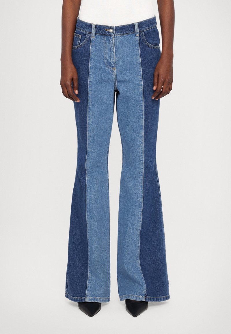 Denim ülestavad teksad erinevates sinistes toonides, kõrge vöökoht, standardsed taskud ja kontrastsed värviplekid.