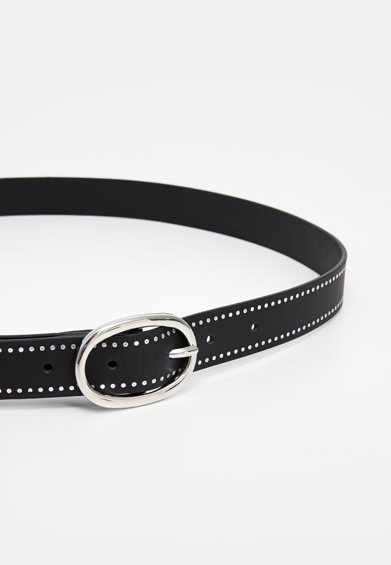 Cinturón de cuero negro con una hebilla ovalada plateada, con pequeños agujeros espaciados uniformemente y puntos blancos a lo largo del borde. Textura suave.