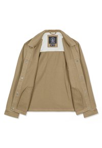 Veste boutonnée couleur brun clair avec col, devant ouvert révélant une doublure intérieure blanche et une étiquette de la marque Volcom à l'intérieur.