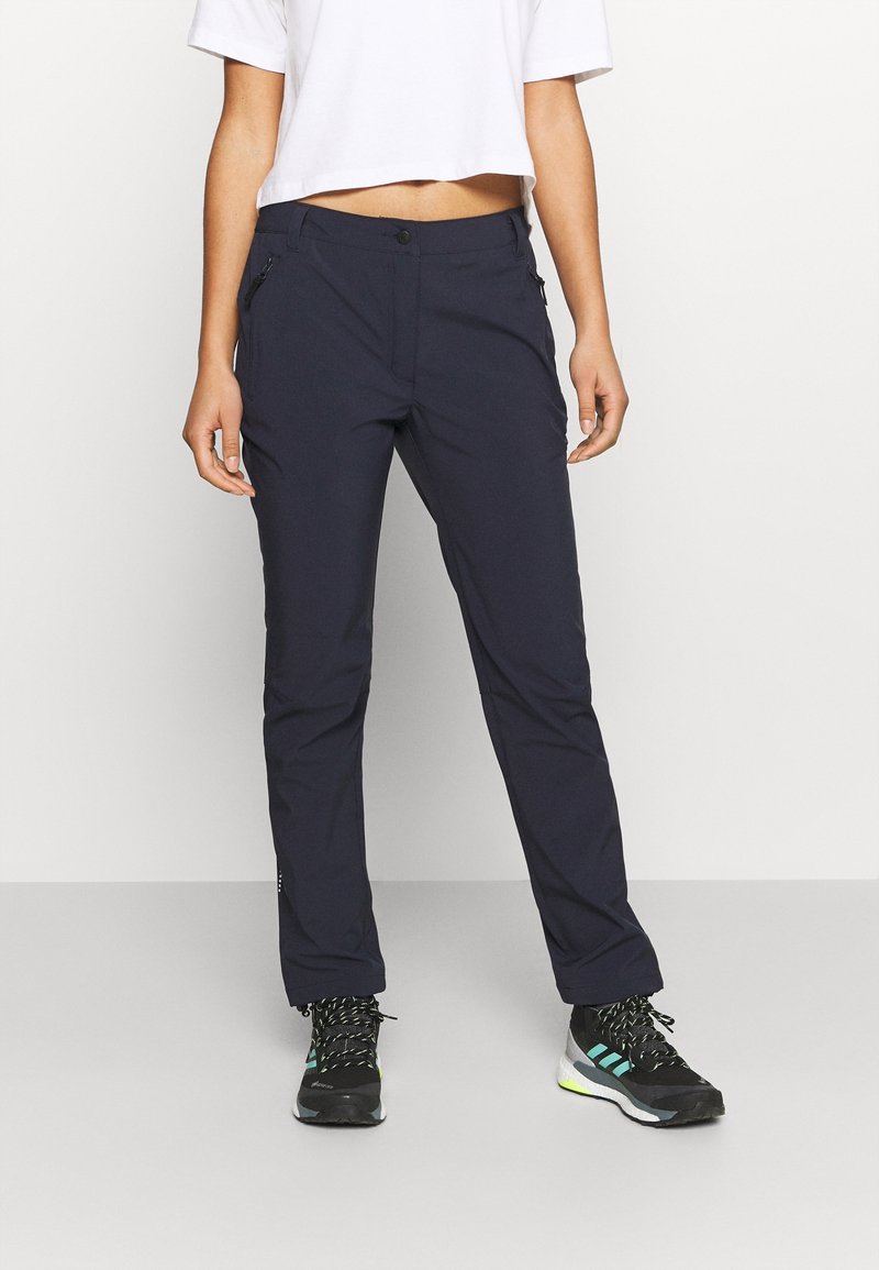 Navyblauwe broek van rekbare stof, met een slim fit, ritszakken en een knoopsluiting, gecombineerd met zwarte sportschoenen.