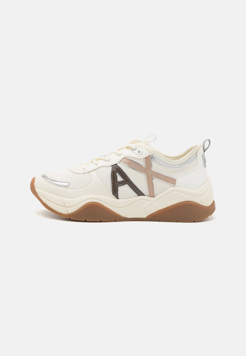 Scarpa sportiva bianca con accenti grigi e beige, materiali testurizzati, suola in gomma e un logo "A" prominente sul lato.