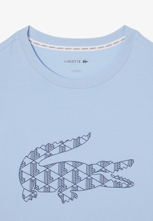 Lichtblauw T-shirt met ronde hals, voorzien van een donkerblauw geometrisch krokodillenlogo op de voorkant en een merkembleem aan de binnenkant van de kraag.