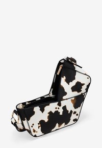 Bolso de mano con estampado de vaca y forma estructurada, que presenta patrones en negro, blanco y marrón. Diseñado con una cremallera y detalles en dorado.