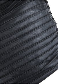 Svart läderväska med upphöjda horisontella ränder, med en texturerad yta och strukturerad form, kompletterad med sömnadsdetaljer.