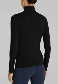 Top nero a maniche lunghe con collo alto fittizio, realizzato in un tessuto liscio e elasticizzato, caratterizzato da un design aderente e una costruzione senza cuciture.
