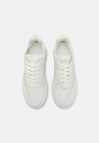 Baskets blanches en cuir, avec des lacets ronds, des détails de couture et une texture lisse. Semelles en caoutchouc surélevées et design épuré.