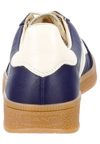 Sneaker in pelle blu navy con accenti bianchi, suola in gomma testurizzata e logo. Caratterizzato da una forma arrotondata e un design a profilo basso.