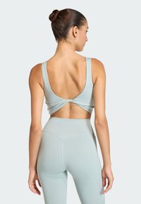 Light blue athletic crop top with wide straps, back twist detail, and matching high-waisted leggings. Smooth texture and fitted design.