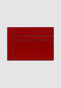 Portacarte in pelle rossa con cuciture blu, dotato di quattro scomparti per carte e logo in rilievo. Texture liscia e design rettangolare sottile.