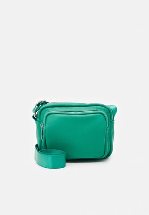 Bolso bandolera pequeño verde con bolsillo frontal con cremallera y correa ajustable sobre fondo blanco.