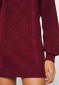 Abito in maglia bordeaux con motivo a treccia, maniche con polsini a costine e una vestibilità comoda. Tessuto testurizzato con orlo senza cuciture.