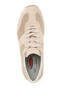 Beige suède sportschoen met meshpanelen, ronde neus, platte veters en een gevoerde binnenzool met een rood en grijs ontwerp.