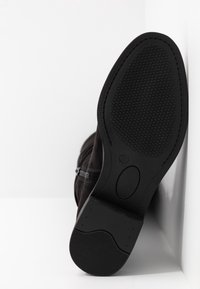 Semelle de botte noire avec grip texturé, taille 37 marquée, présentée sur un fond blanc à coins.