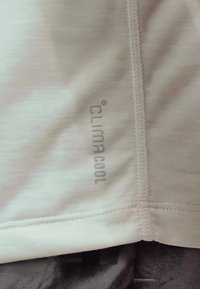 Tissu athlétique gris clair avec des détails de couture ; présente le logo "climacool" en argent sur le côté. Design texturé et évacuant l'humidité.