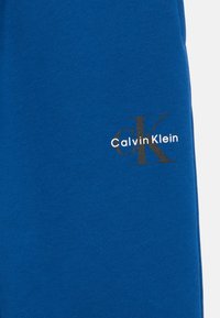 Μπλε βαμβακερό φούτερ με μικρό λογότυπο Calvin Klein σε λευκό και μαύρο στη αριστερή πλευρά. Λείος υφή, κ casual σχέδιο.