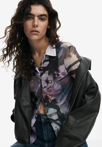 Multicolored floral-patterned shirt with a white collar and buttons, paired with a black leather jacket, denim jeans.