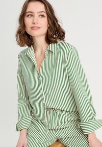 Chemise boutonnée à rayures vertes et blanches avec des manches longues, dotée d'un col et d'une taille à cordon, fabriquée en tissu léger.