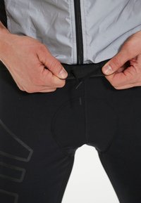 Svarta atletiska leggings med ett texturerat mönster och elastisk midja, med ett runt insatsområde och justerbar dragsko för passform.