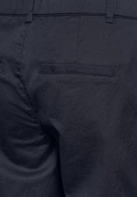 Navyblauwe broek met een gladde textuur, voorzien van een achterzak met een flapontwerp en vlakke stiksels.