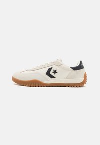 Weiße Canvas-Sneaker mit einem schwarzen Stern-Design, Gummisohle und strukturierten Akzenten. Die glatten Schnürsenkel runden das Erscheinungsbild ab.