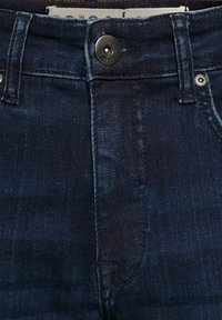 Jean en denim bleu foncé avec une taille haute, dotés d'une fermeture à bouton à l'avant, de cinq poches et de détails de couture subtils.