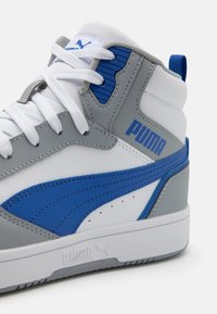 Sivi i bijeli visoki tenisice s plavim naglaskom, s teksturiranom kožom, podstavljenim ovratnikom i gumenim potplatom. Puma logo s bočne strane.