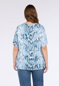 Top blu con stampa a serpente, maniche corte e scollatura rotonda, caratterizzato da un dettaglio a chiave sulla parte posteriore e una vestibilità morbida.