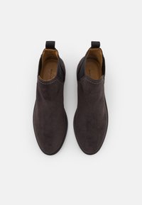 Tummanharmaat mokkanahka nilkkurit, joissa on joustavat sivupaneelit, pyöreä kärki ja vetopidike kannassa helppoa pukemista varten. Sujuva vuori.