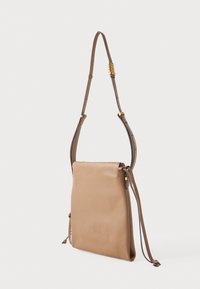 Šviesiai rudos odos kryžminė rankinė su lygiu paviršiumi, reguliuojama juosta, auksinėmis detalėmis ir minimalistiniu dizainu. Nėra matomų užsegimų.