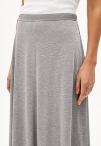 Light gray, knee-length skirt made of soft fabric. Features a wide, textured waistband with embossed branding. Smooth, draped design.
