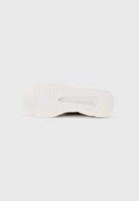 Hvite sneakersåle, med en teksturert gummisåle og zigzag mønster, samt merkevarenavnet "KARL LAGERFELD" preget på siden.