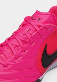 Φωτεινό ροζ αθλητικό παπούτσι Nike με μαύρο λογότυπο Swoosh και ροζ κορδόνια που ταιριάζουν, εμφανιζόμενο σε κοντινή λήψη σε λευκό φόντο.