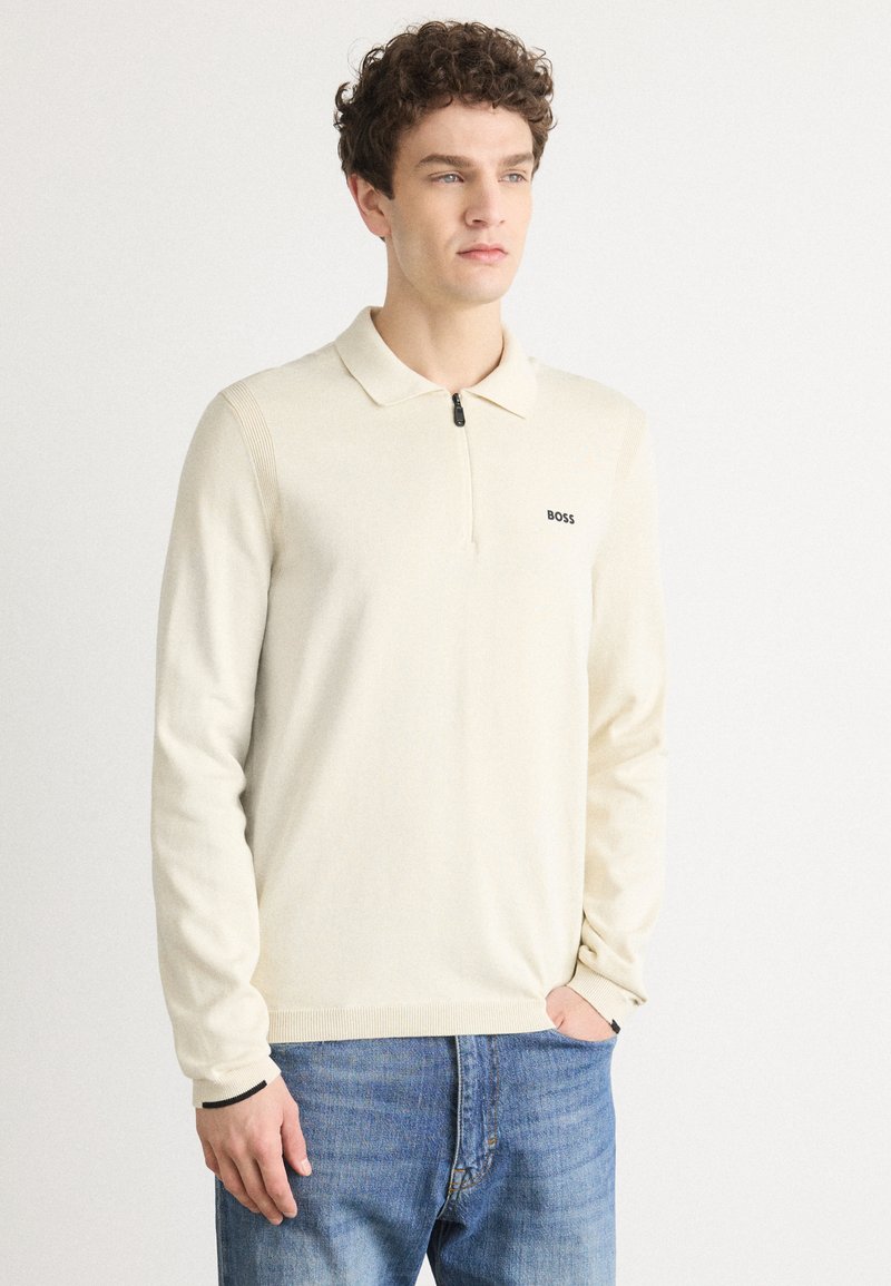Cream lightweight polo sweater with a zipper closure, long sleeves, and ribbed accents. Features a small black "BOSS" logo on the chest.