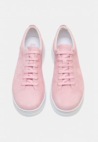 Pink suede sneakers with white rubber soles, featuring flat laces and a rounded toe. Smooth texture with minimal branding on the tongue.