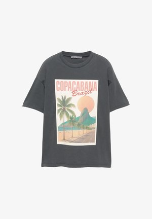 Sivina prevelika majica s printom grafike plaže Copacabana, koja prikazuje palme, planinu i sunce u pastelnih bojama.