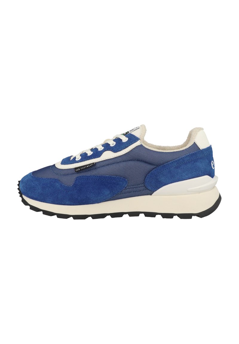 Modré semišové a síťované tenisky s masivní bílou mezipodešví, černou podešví a plochými šňůrkami. Hlavní designové prvky zahrnují texturovaný svršek a detail loga.