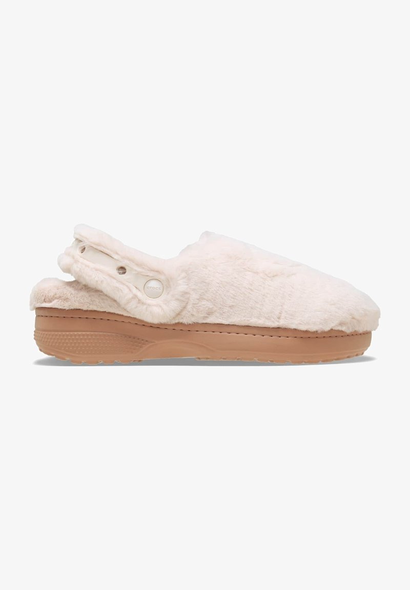 Chaussons blancs pelucheux avec une semelle en caoutchouc beige, design enfilement et accents de boutons sur le côté. La texture douce ajoute du confort.