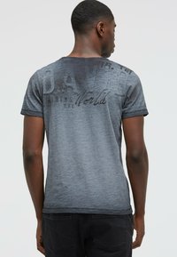 Short-sleeve gray t-shirt featuring a faded, textured finish with black graphic text on the back. Casual fit with a round neckline.